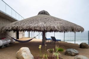 Primo Tapia的住宿－Triton's Playhouse Beachfront，海滩上的吊床和小屋