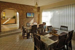 a dining room with tables and chairs and a brick wall at Mall Guesthouse in Vanderbijlpark