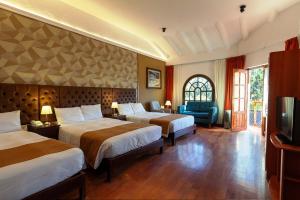 Cette chambre comprend deux lits et une télévision. dans l'établissement Inti Punku Valle Sagrado Hotel, à Urubamba