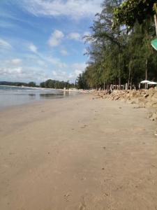 a sandy beach with trees and the ocean at Na Na Twinhouse in Bang Tao Beach