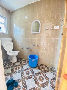 a bathroom with a toilet and a blue bucket at Pall Residency in Srinagar