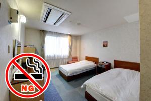 a hotel room with two beds and a no smoking sign at ホテルスターらんど in Tsuru 