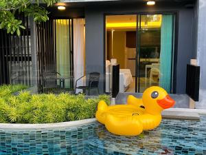 a yellow rubber ducky sitting on the side of a pool at The aristo-access pool room Surin beach in Phuket