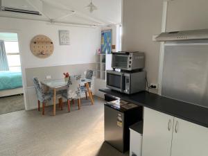 a kitchen and dining room with a table and a microwave at Mill Corner Studios in Matamata