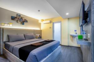 a bedroom with a large bed and a television at Infiniti Hotel in Jakarta