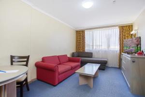 a living room with a red couch and a table at Mid City Motel Warrnambool in Warrnambool