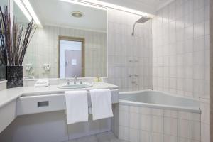 Mid City Motel Warrnambool في وارنامبول: حمام أبيض مع حوض ومغسلة