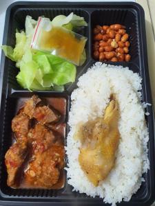 eine schwarze Lunchbox mit Reis, Fleisch und Gemüse in der Unterkunft Nha Xanh Ha Long Homestay in Hạ Long
