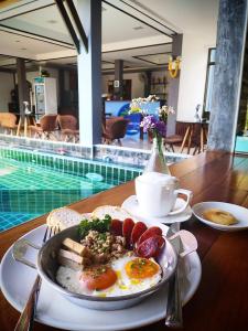 un plato de desayuno con huevos y pan junto a la piscina en Billabong Hotel and Cafe en Baan Tai