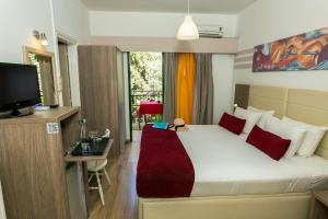 a bedroom with a bed and a desk and a television at Fitosinn Hotel in Paphos