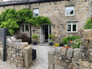 een stenen huis met een stenen muur ervoor bij The Courtyard Cottage, Timble near Harrogate in Timble