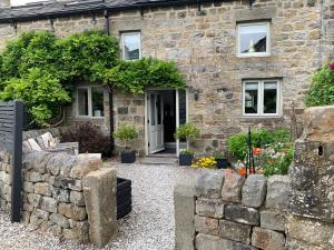 a stone house with a stone wall in front of it at The Courtyard Cottage, Timble near Harrogate in Timble