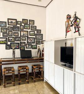 a living room with a television and a wall of pictures at Hostel Wees een Kind in Malang