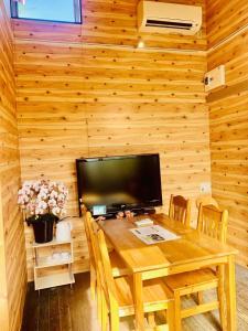 ein hölzernes Esszimmer mit einem Tisch und einem TV in der Unterkunft ハセノ島　Hotel　Cottage in Kamakura