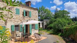 ein Haus mit einem Tisch, Stühlen und einem Sonnenschirm in der Unterkunft Guyor in Le Bez