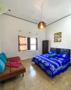 1 dormitorio con cama, sofá y ventana en Hostel Wees een Kind, en Malang