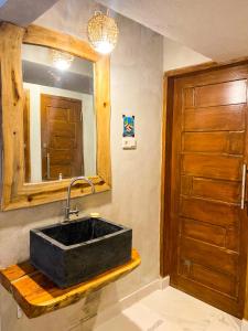 a bathroom with a black sink and a mirror at Hostel Wees een Kind in Malang