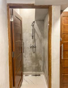 a shower stall in a bathroom with a door at Hostel Wees een Kind in Malang