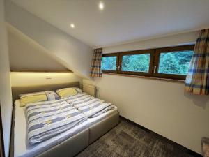 ein kleines Schlafzimmer mit einem Bett und zwei Fenstern in der Unterkunft Haus Wagrain in Wagrain