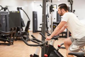 Ein Mann, der in einem Fitnessstudio Fahrrad fährt. in der Unterkunft Apollo Beach in Faliraki