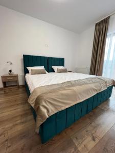 un grande letto con testiera blu in una camera da letto di Aparthotel Plevnei 3 a Cluj-Napoca