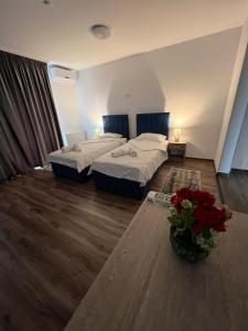 a room with two beds and a vase of red roses at Aparthotel Plevnei4 in Cluj-Napoca