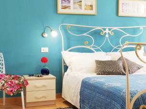 a bedroom with blue walls and a bed and a side table at Villa Oleandro in Scopello
