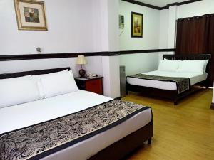 a hotel room with two beds and a night stand at The Gabriella Bed and Breakfast in Tagbilaran City
