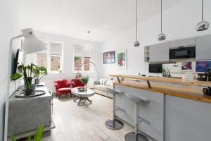 a kitchen and living room with white cabinets and red chairs at Apartament "Holy" in Poznań