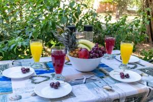 a table with a bowl of fruit and glasses of juice at Fotis house in Afantou