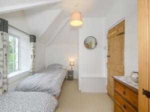 two beds in a small room with a window at Bluebell Cottage in Tavistock