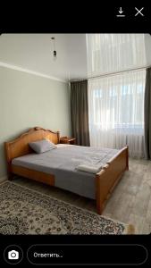 1 dormitorio con cama y ventana grande en Квартира посуточно, en Uralsk