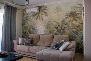 een woonkamer met een bank en een muurschildering van palmbomen bij Sul House in Albufeira