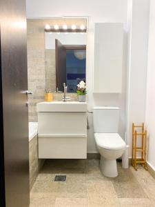 uma casa de banho com um WC, um lavatório e um espelho. em VR2 Central Apartment em Bucareste
