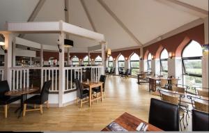 een restaurant met houten tafels, stoelen en ramen bij Luxury Lodge - Hoburne Devon Bay in Paignton