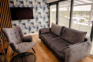 salon ze skórzaną kanapą i 2 krzesłami w obiekcie Apartamenty Białe Tomasza 4 w mieście Augustów