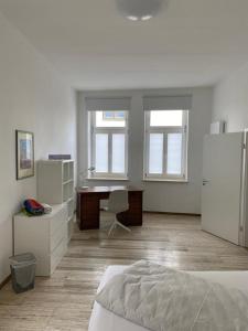 Cette chambre blanche comprend un bureau et un lit. dans l'établissement Apartment Van Eß Hof - Altstadt Warburg, à Warburg