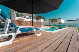a wooden deck with an umbrella and a pool at Quinta dos Passarinhos in Nadadouro