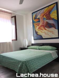 um quarto com uma cama com um quadro na parede em Lachea House appartamento sul mare dei Ciclopi em Aci Castello