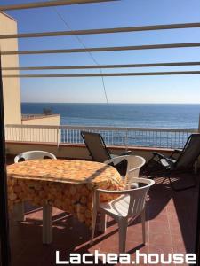 uma mesa e cadeiras numa varanda com o oceano em Lachea House appartamento sul mare dei Ciclopi em Aci Castello