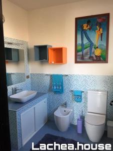 uma casa de banho com um lavatório, um WC e uma pintura em Lachea House appartamento sul mare dei Ciclopi em Aci Castello