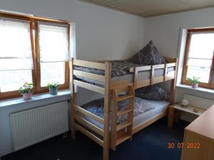 a bedroom with two bunk beds and two windows at Ferienwohnung Schwarz in Röttenbach