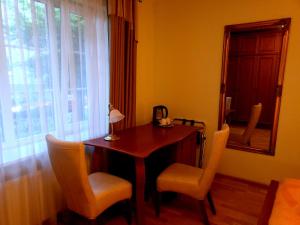 a room with a table and two chairs and a mirror at Guest House Poilsis Jums in Klaipėda