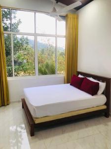 sypialnia z dużym łóżkiem przed oknem w obiekcie Kandy River Garden w mieście Kandy