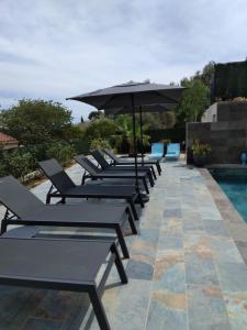 a row of lounge chairs and an umbrella next to a pool at Le Spot 577 in La Ciotat