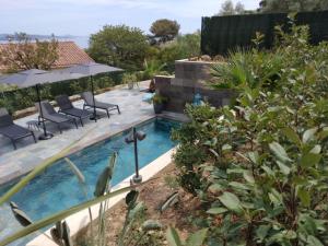 a backyard with a swimming pool with chairs and umbrellas at Le Spot 577 in La Ciotat