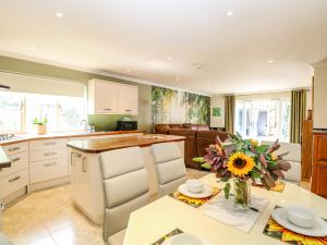a kitchen and living room with a table with a vase of flowers at Birch Cottage in Norwich