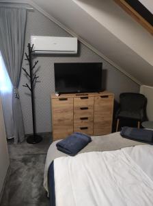 ein Schlafzimmer mit einem TV, einem Bett und einer Kommode in der Unterkunft Agroturystyka Klimat in Bircza