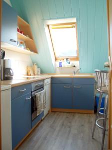 a blue kitchen with a sink and a window at Ferienwohnung Prinke in Niedertrebra