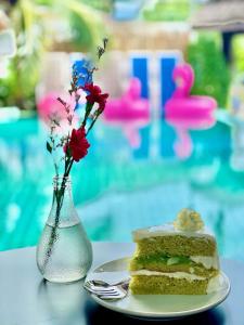 a plate with a cake and a vase with flowers at Billabong Hostel in Baan Tai